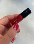 Hand holding a small bottle of HOOPLA Pink Foil - Clean Nail Polish with glittery pink polish applied on the nails, reflecting clean beauty and vegan nail treatments.