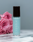 Bottle of Sky - Clean Nail Polish in a soft blue shade by HOOPLA, placed on a marble surface with pink roses in the background, showcasing a clean beauty nail treatment.