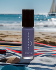 Newport Love - Clean Nail Polish in a soft purple shade by HOOPLA, shown on a beach towel with a coastal background and a sailboat on the ocean.