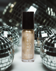 Small bottle of Gold Foil - Clean Nail Polish with shimmering gold polish surrounded by reflective silver disco balls, suggesting a festive and glamorous vibe.