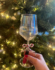 Hand holding a bottle of Pink Foil - Clean Nail Polish with matching painted nails in front of a decorated Christmas tree lighted with white fairy lights.