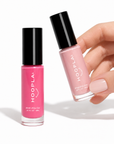 Hand holding a bottle of light pink nail polish next to a standing bottle of bright pink polish, showcasing the Clean Pocket Nail Polish Duo - Posy in a clean beauty style.