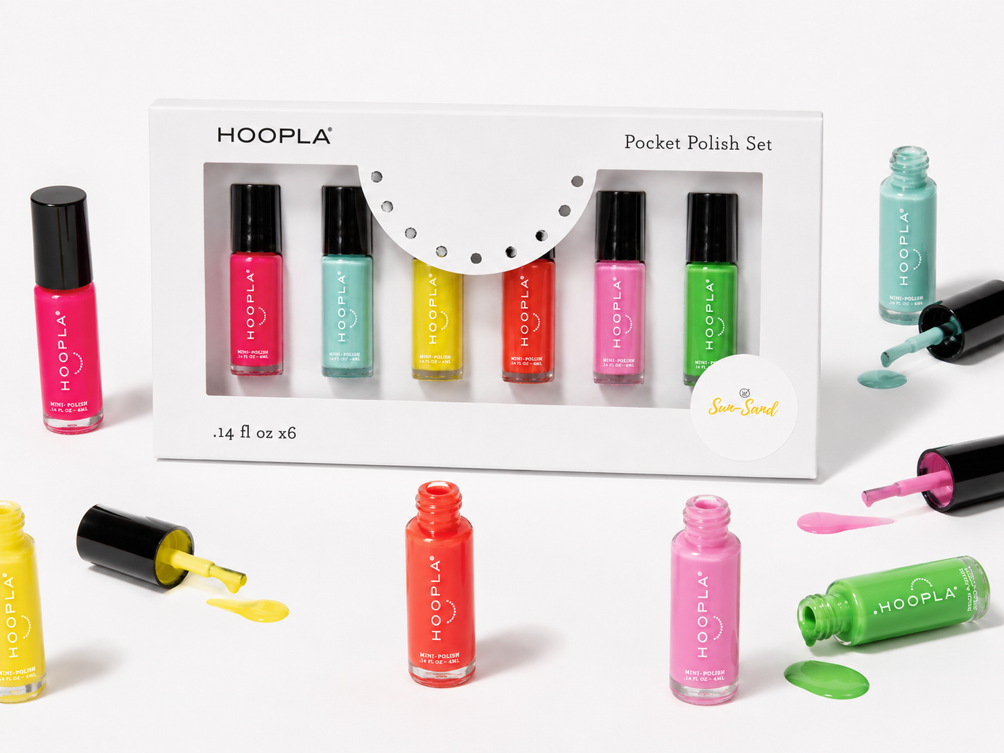 Brightly colored nail polish bottles in shades of pink, turquoise, yellow, red, purple, and green from the Pocket Polish Set - Sun+Sand arranged alongside the boxed set with spilled polish accents.