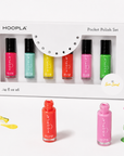 Brightly colored nail polish bottles in shades of pink, turquoise, yellow, red, purple, and green from the Pocket Polish Set - Sun+Sand arranged alongside the boxed set with spilled polish accents.